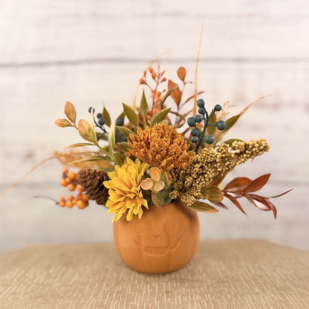 Harvest Grin smiling pumpkin with yellow and orange faux fall flowers, berries and autumn leaves