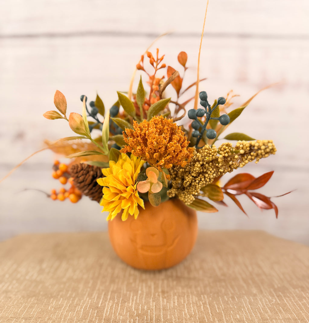 Harvest Grin smiling pumpkin with yellow and orange faux fall flowers, berries and autumn leaves