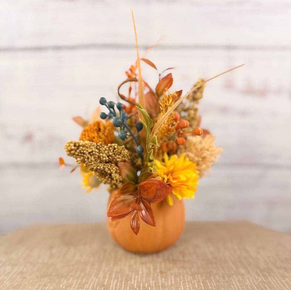 Harvest Grin smiling pumpkin with yellow and orange faux fall flowers, berries and autumn leaves