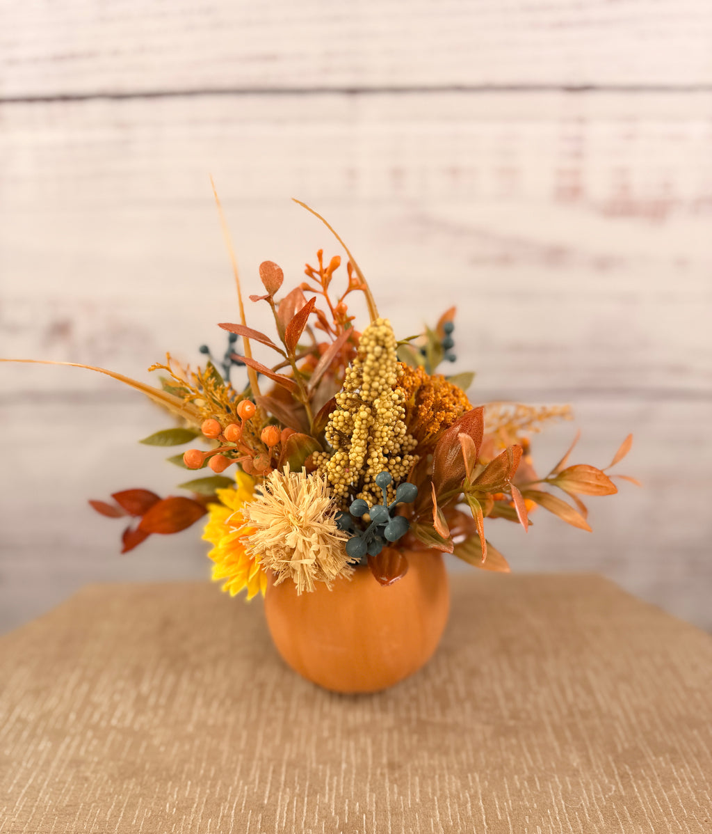 Harvest Grin smiling pumpkin with yellow and orange faux fall flowers, berries and autumn leaves