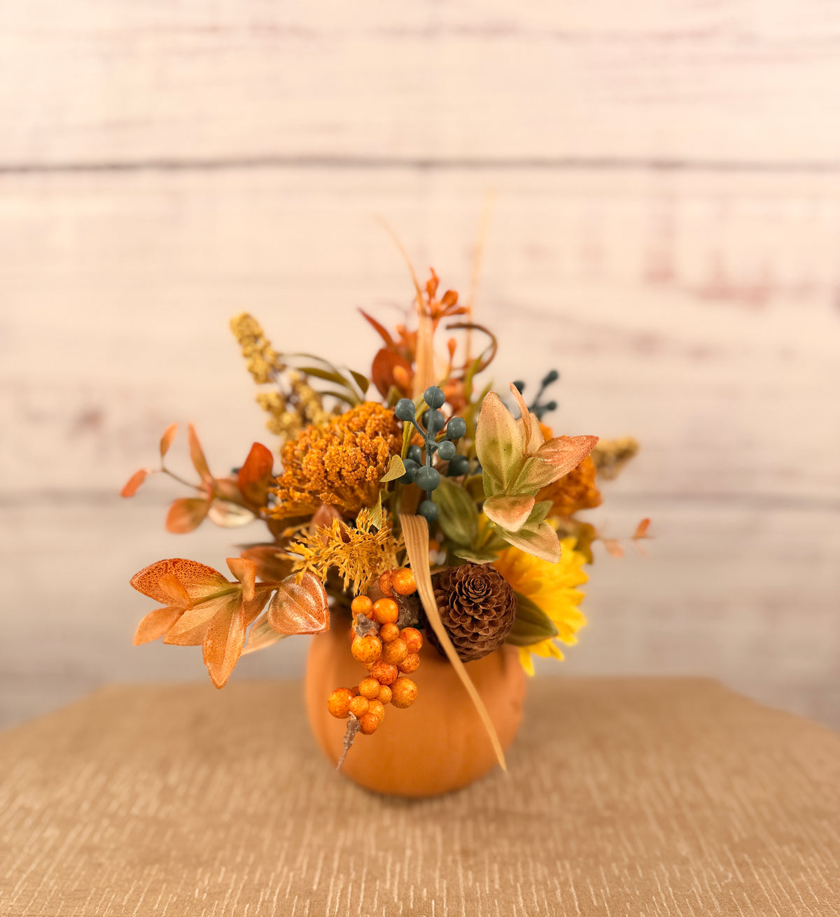 Harvest Grin smiling pumpkin with yellow and orange faux fall flowers, berries and autumn leaves