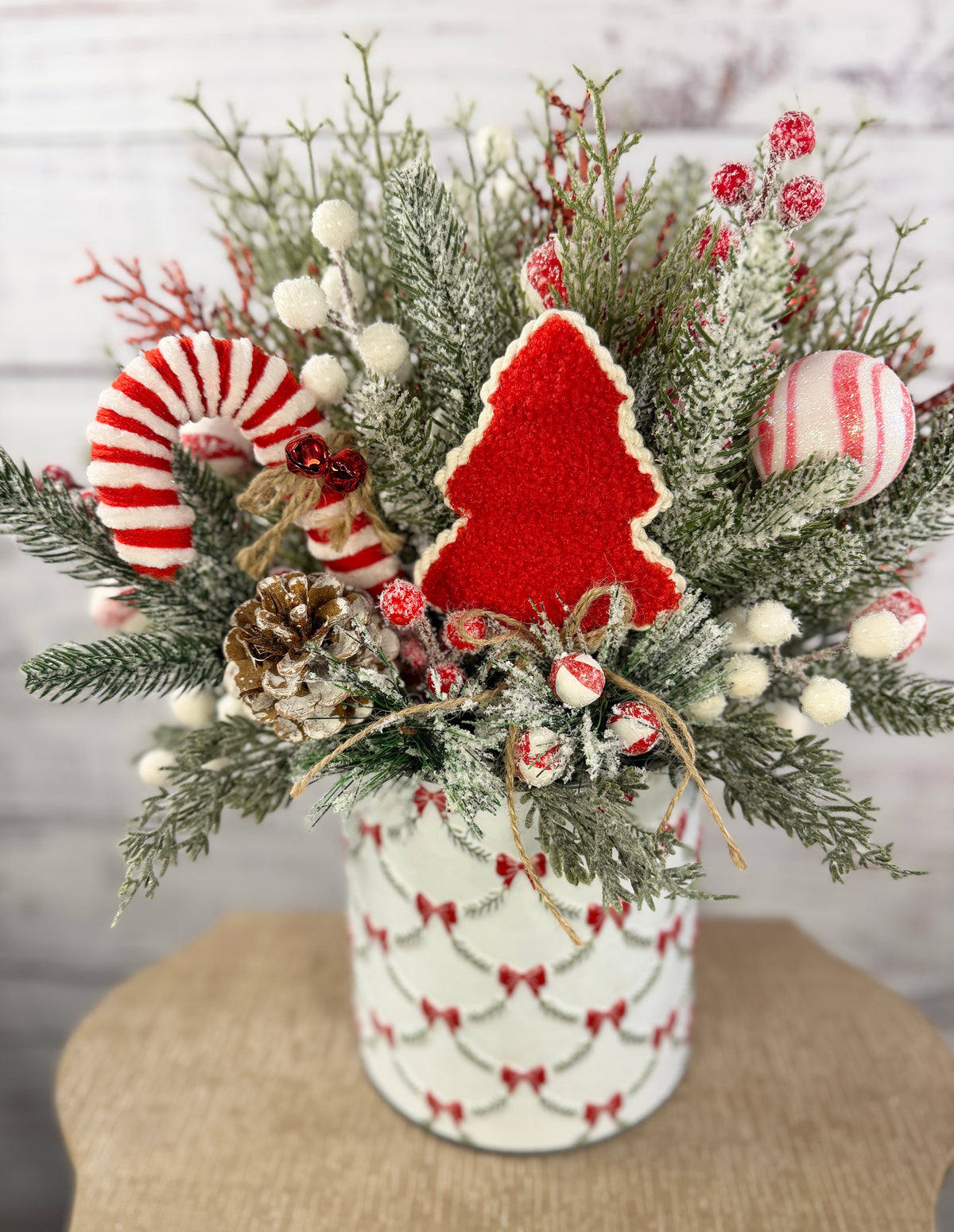 Candy cane and red tree Christmas arrangement with snowy greenery in holiday tin