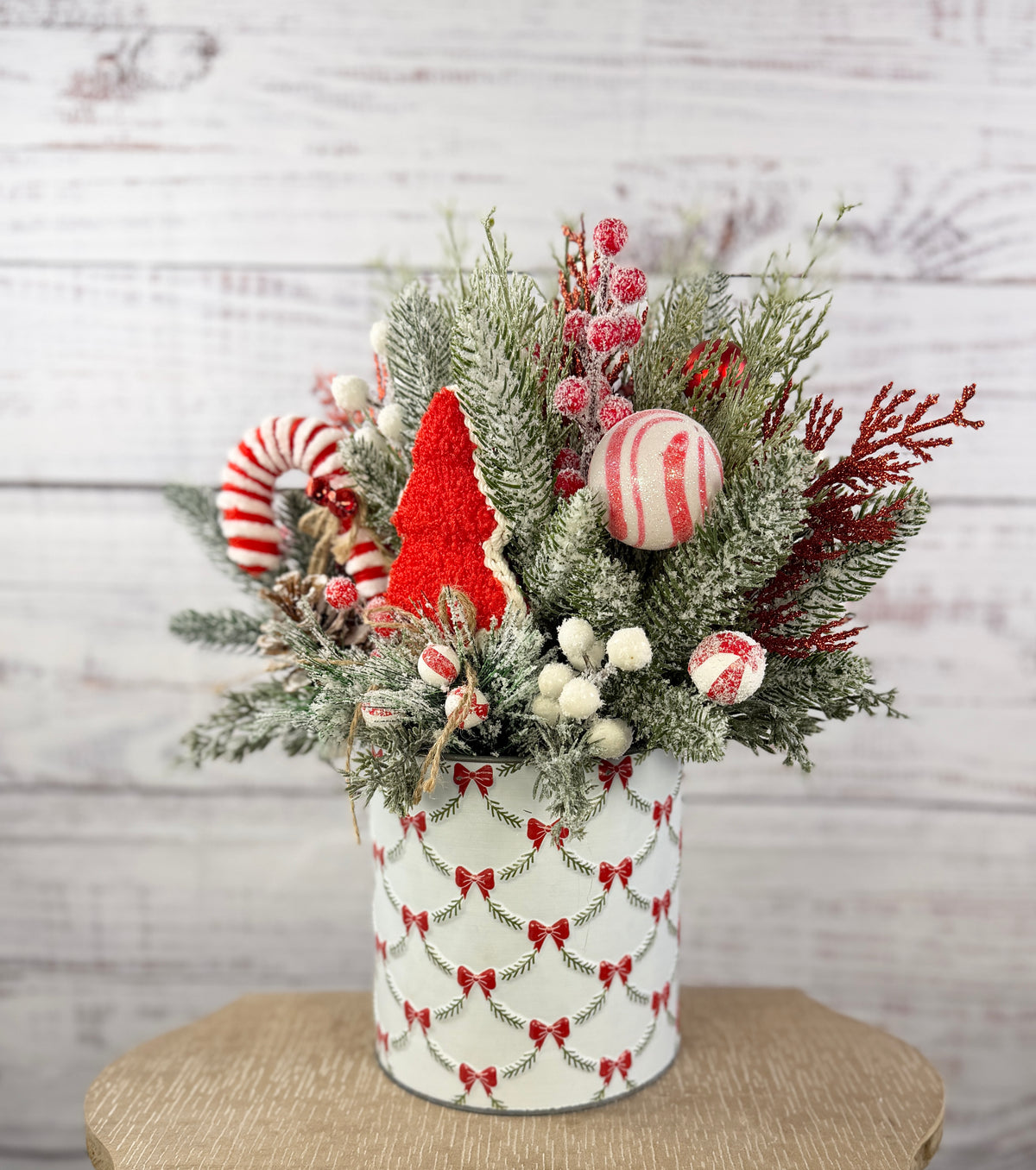 Candy cane and red tree Christmas arrangement with snowy greenery in holiday tin