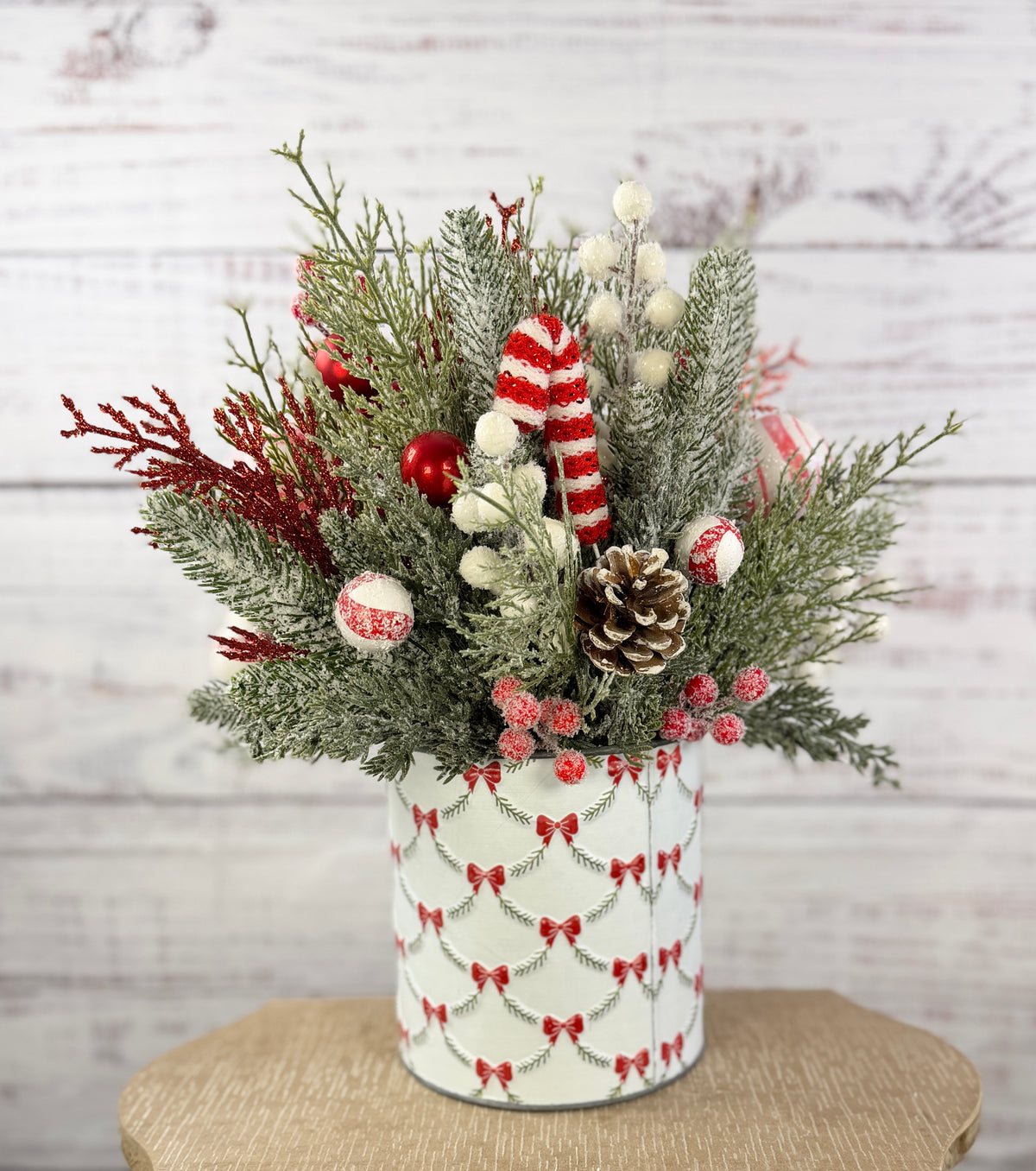 Candy cane and red tree Christmas arrangement with snowy greenery in holiday tin