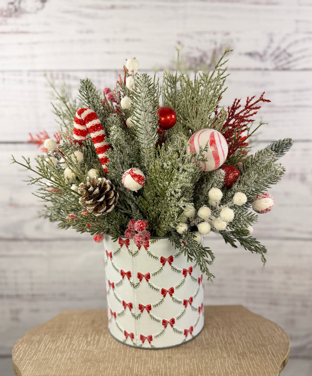 Candy cane and red tree Christmas arrangement with snowy greenery in holiday tin