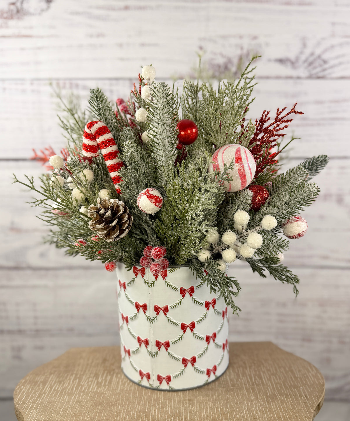 Candy cane and red tree Christmas arrangement with snowy greenery in holiday tin