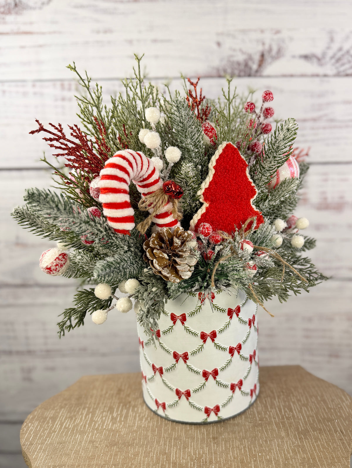 Candy cane and red tree Christmas arrangement with snowy greenery in holiday tin