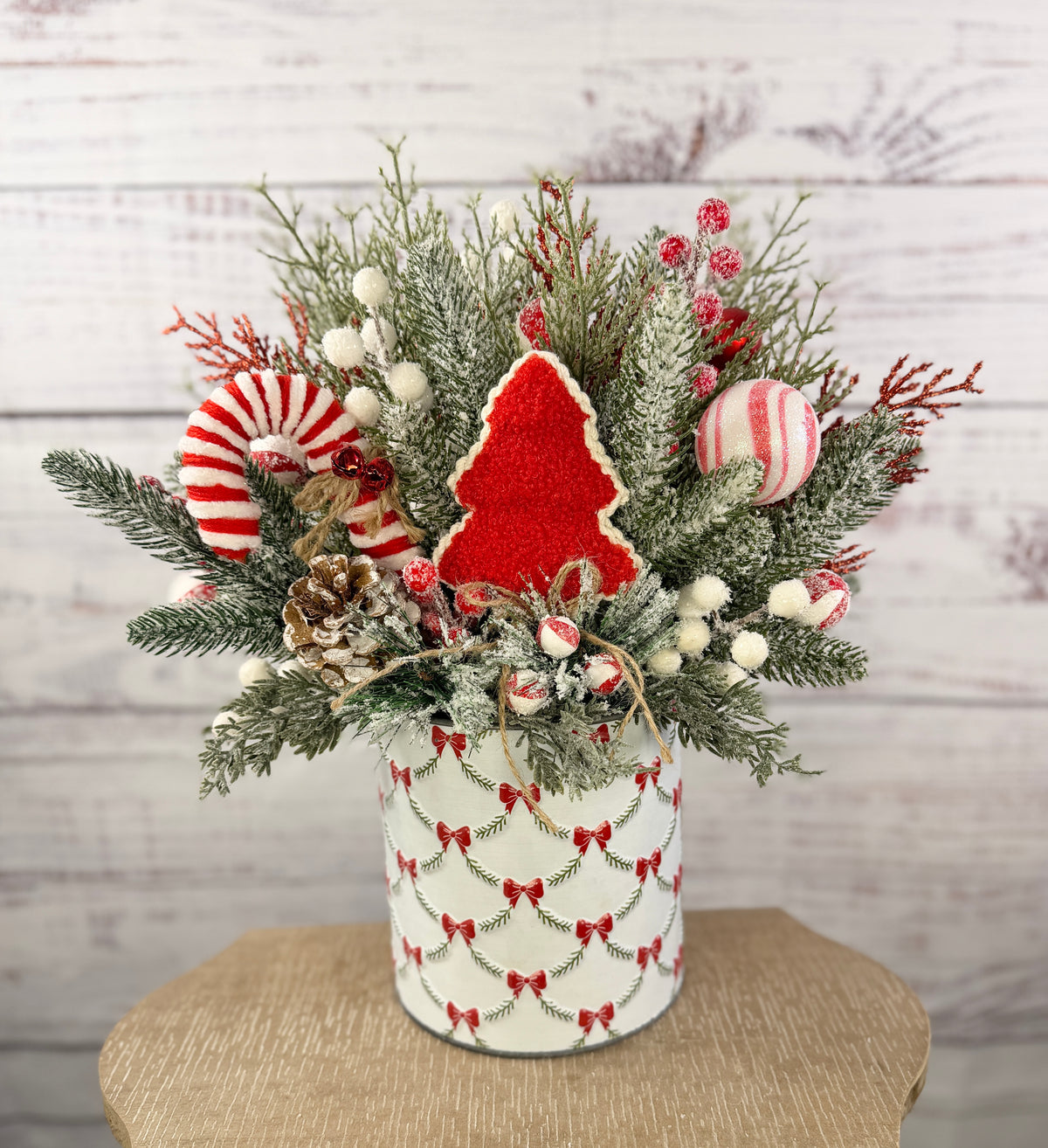 Candy cane and red tree Christmas arrangement with snowy greenery in holiday tin