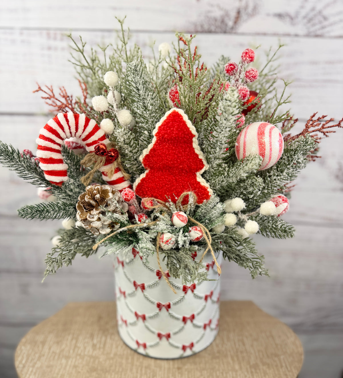 Candy cane and red tree Christmas arrangement with snowy greenery in holiday tin