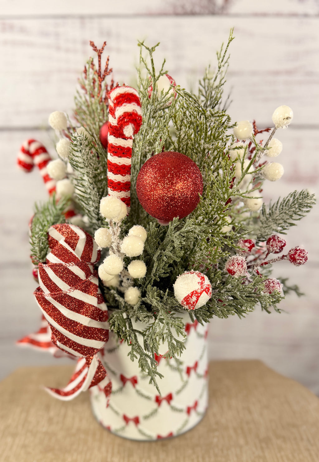 Handmade peppermint Christmas arrangement, side view showing red ornaments and snowy berries