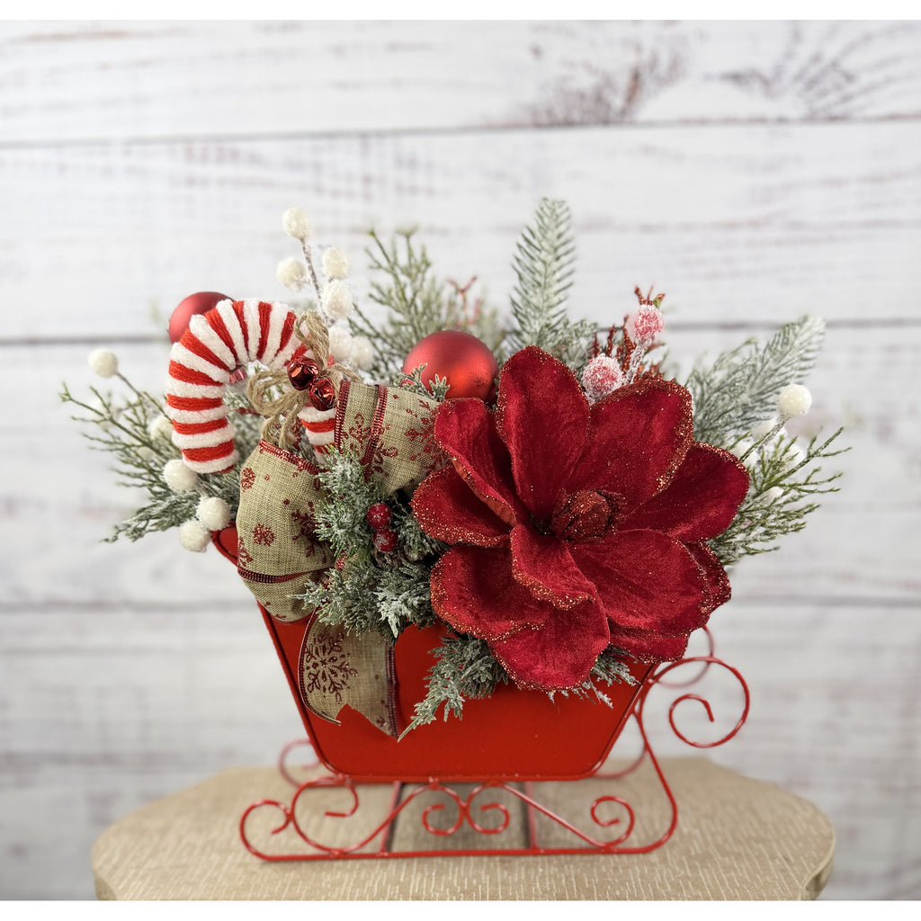 Red Christmas sleigh centerpiece with candy cane and snowy greenery