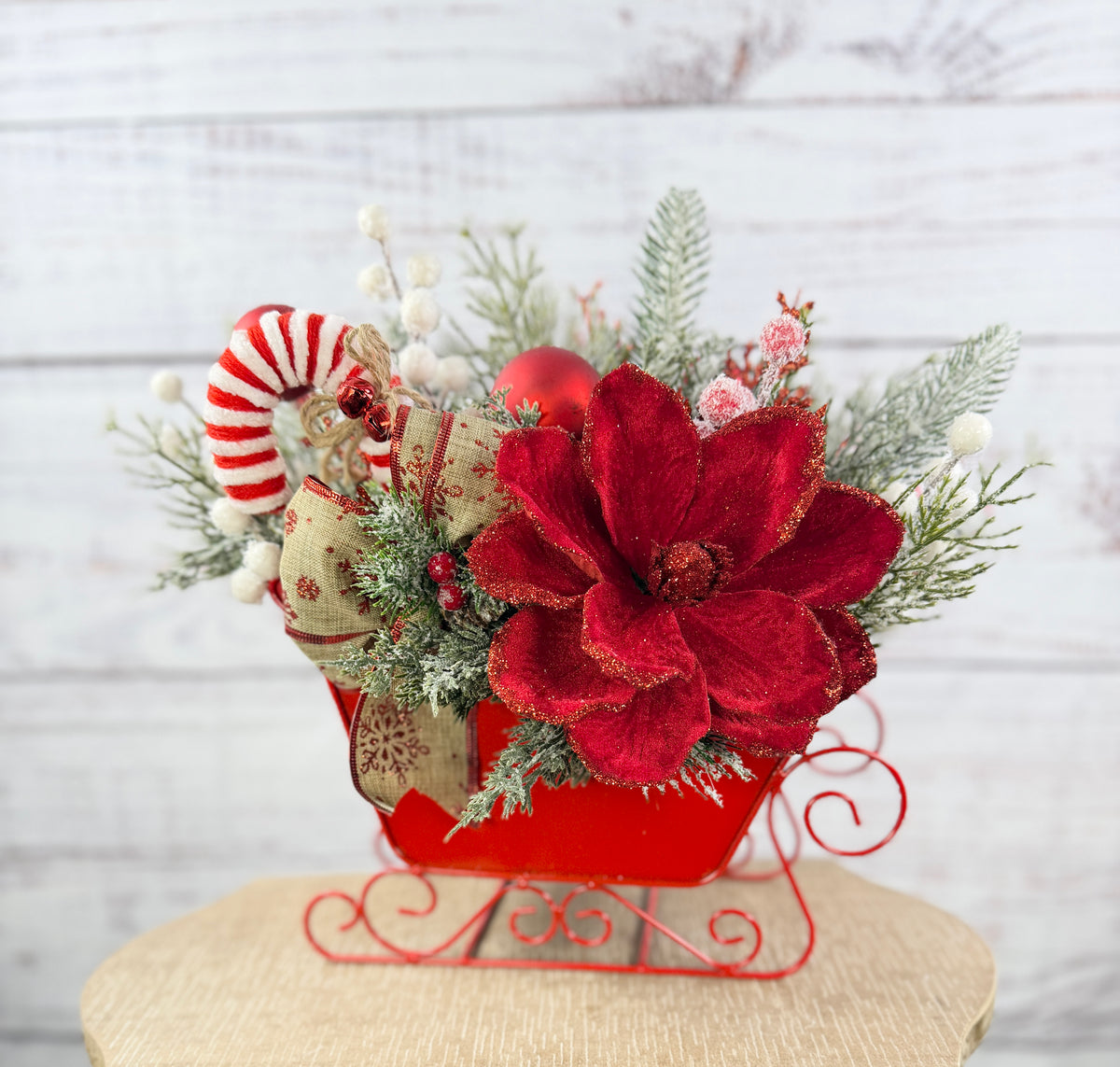 Elevated front view of red sleigh with candy cane and red flower