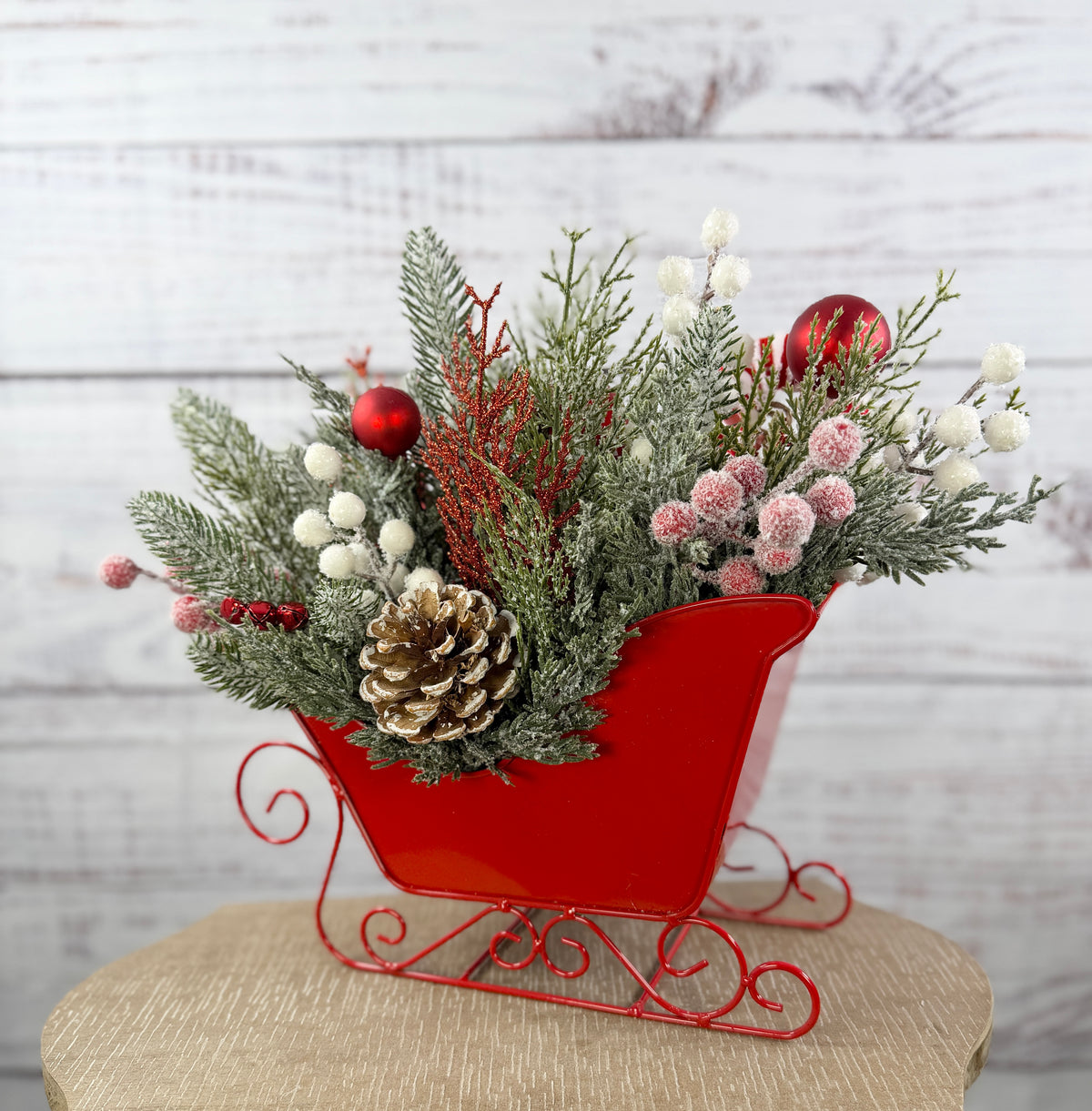 Finished back of Christmas sleigh with snowy greenery and pinecone