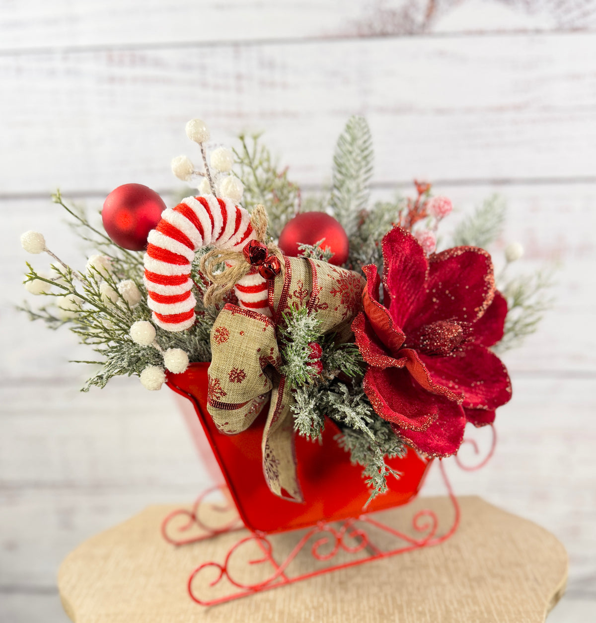 Angled front of red Christmas sleigh with candy cane and snowflake ribbon