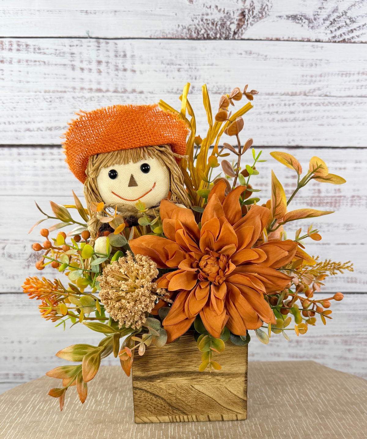Sweet Scarecrow fall arrangement with smiling scarecrow, orange flowers and autumn foliage in a rustic wood cube box