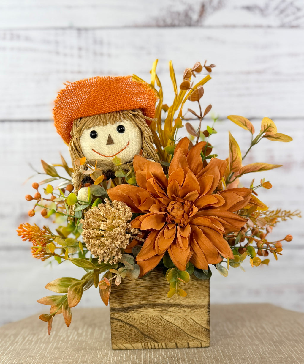 Sweet Scarecrow fall arrangement with smiling scarecrow, orange flowers and autumn foliage in a rustic wood cube box