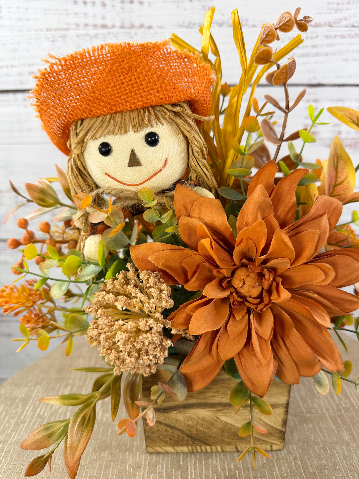 Sweet Scarecrow fall arrangement with smiling scarecrow, orange flowers and autumn foliage in a rustic wood cube box